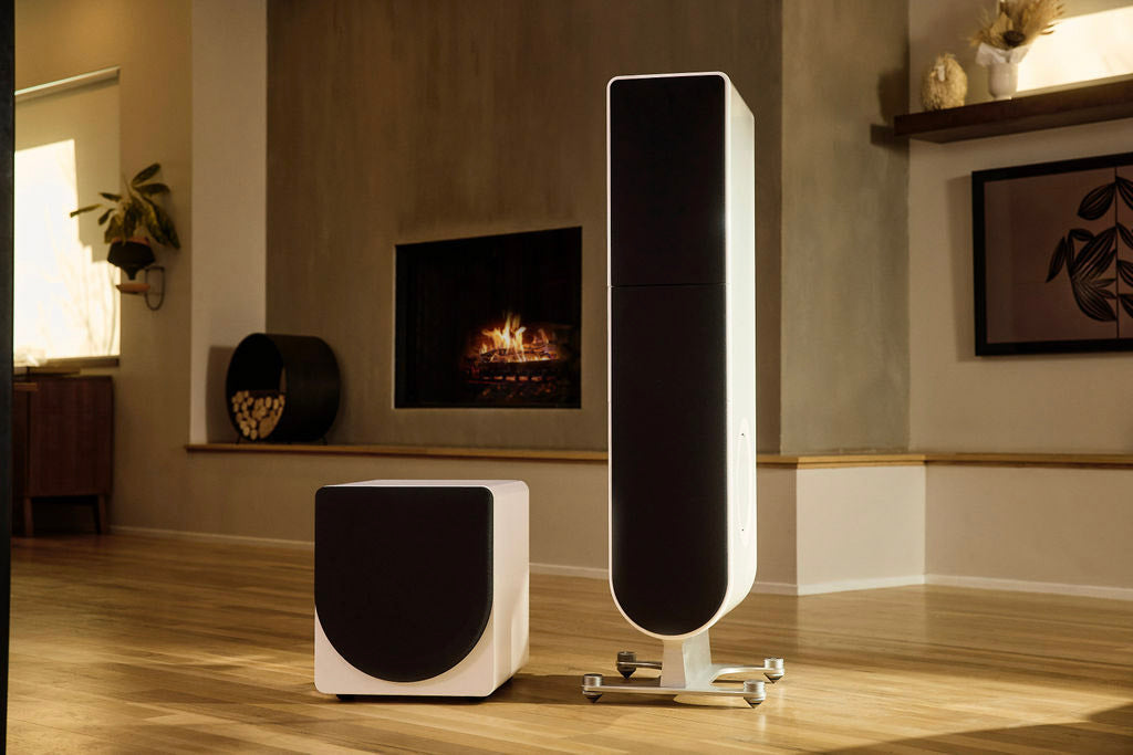 A white PS Audio loudspeaker and subwoofer in a warm listening room