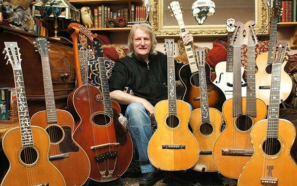Paul Brett seated with guitars.