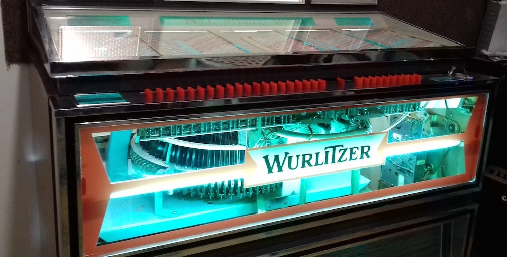 A 1967 USA made Wurlitzer "Americana" jukebox, able to play 200 selections (100 records). It features custom see-through front glass in place of the original lining, for better mechanics and for turntable visibility.