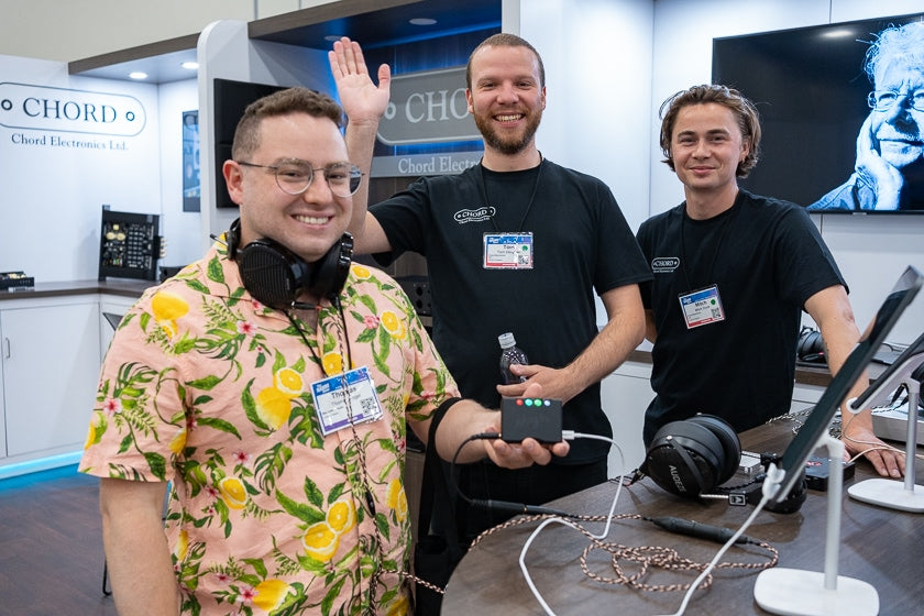 Thomas Fogel holding the new Chord Mojo 2 DAC/headphone amplifier, with the help of Tom Vaughn and Mitch Duce of Chord and some sweet Audeze headphones.