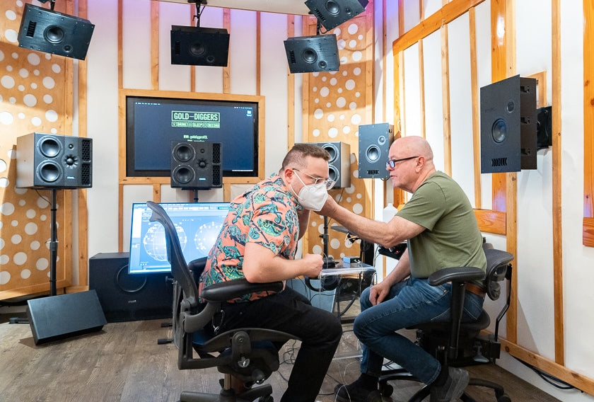 Gus Skinas fitting Thomas Fogel with positioning microphones. Thomas then faced the speakers, and the microphones calibrated the system to his precise location. Later the microphones are removed and replaced with headphones.