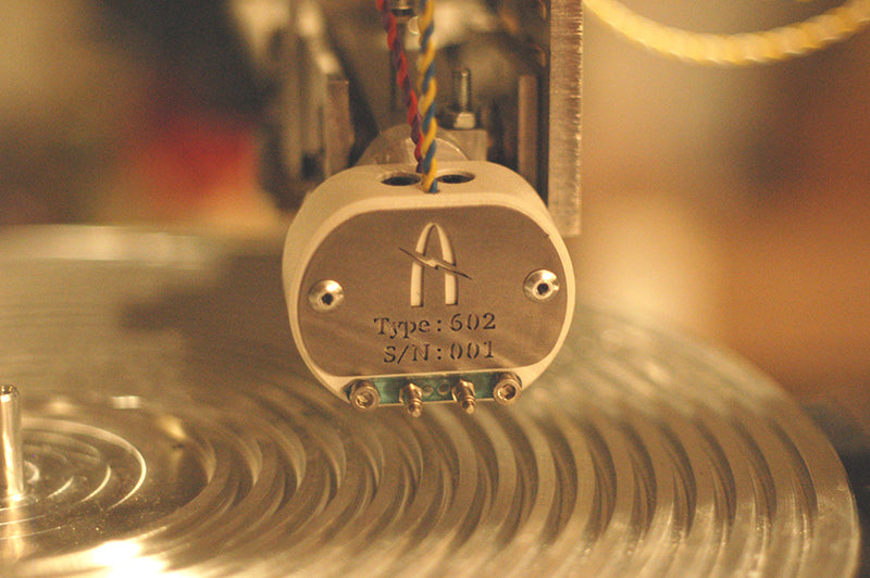 Agnew Analog Reference Instrument Type 602, a new-generation stereophonic cutterhead for disk recording and mastering systems, pictured above the Agnew Analog Type 6112 vacuum platter, on an Agnew Analog Type 613 disk mastering lathe, driven by an Agnew Analog Series 890 cutting amplifier rack.